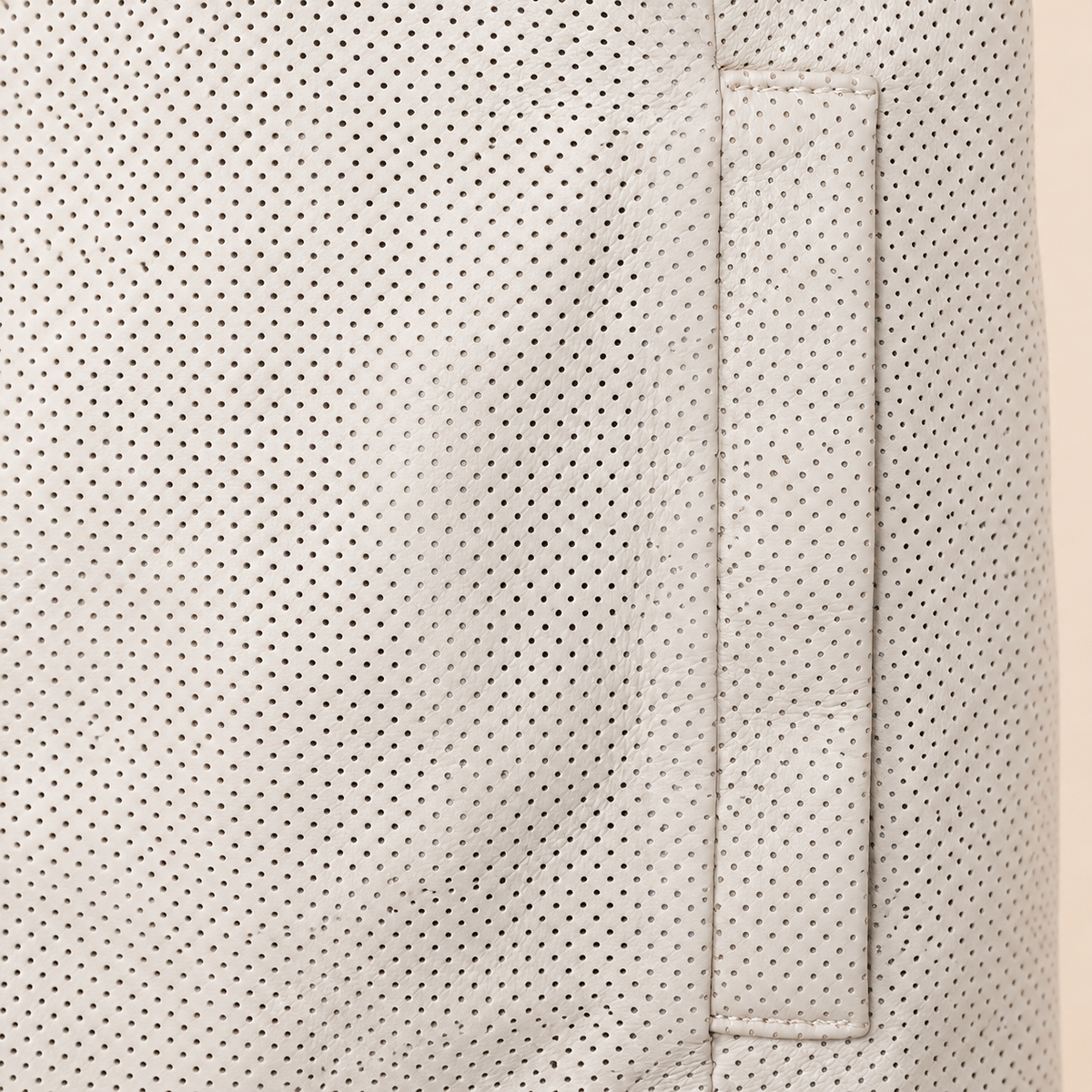 Close-up of the ivory perforated lambskin and vertical welt pocket stitching.