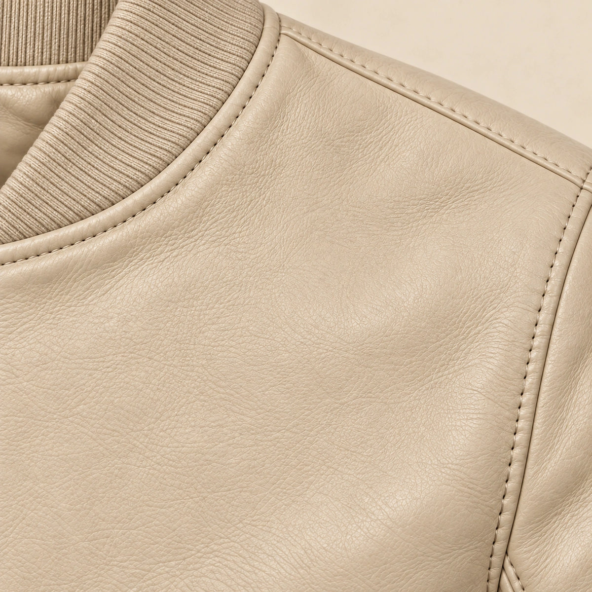 Close-up of beige bomber jacket leather grain and seam stitching