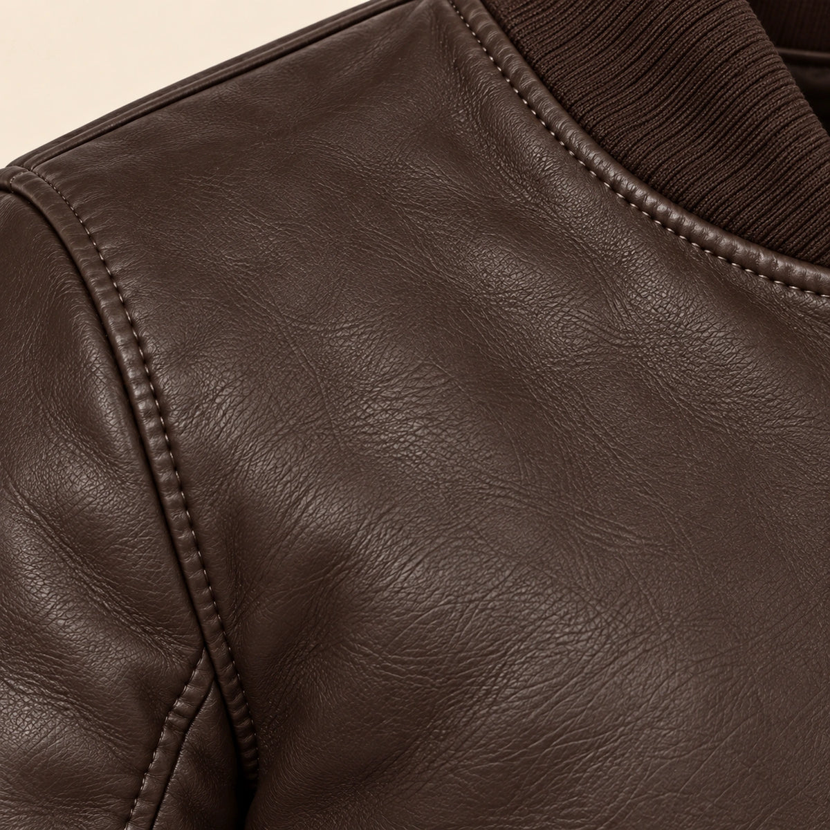 Close-up of brown bomber jacket leather grain and seam stitching