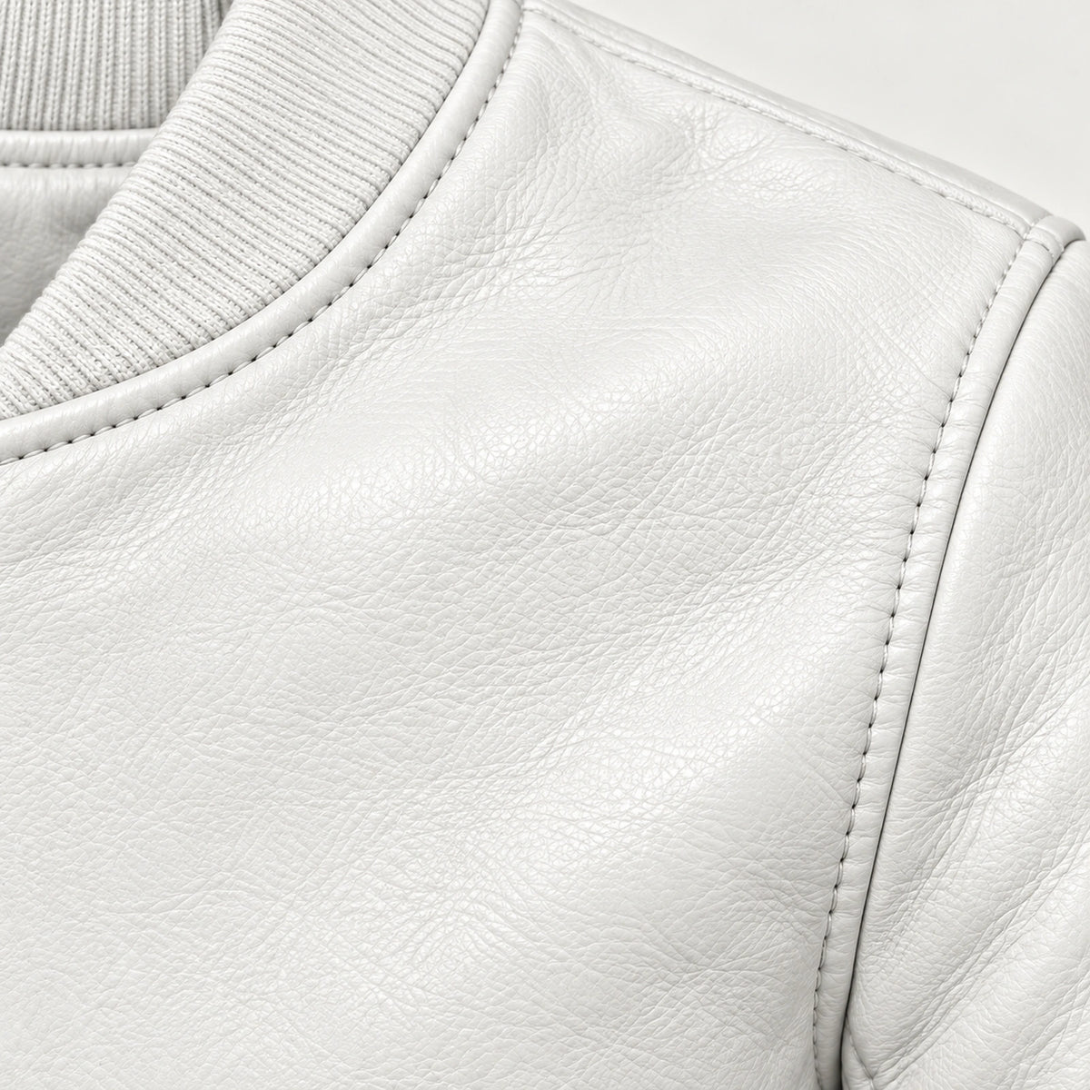 Close-up of white bomber jacket leather grain and seam stitching